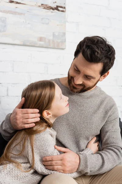 Glücklicher Vater und Tochter, die sich im Wohnzimmer umarmen und anschauen — Stockfoto