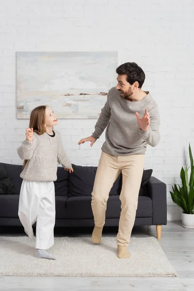 Full length of excited man with preteen daughter looking at each other while dancing in living room — Stock Photo