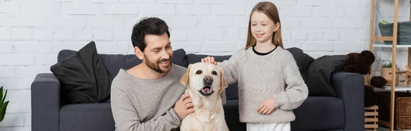 Labrador dog sticking out tongue near smiling bearded man and preteen girl, banner — Stock Photo