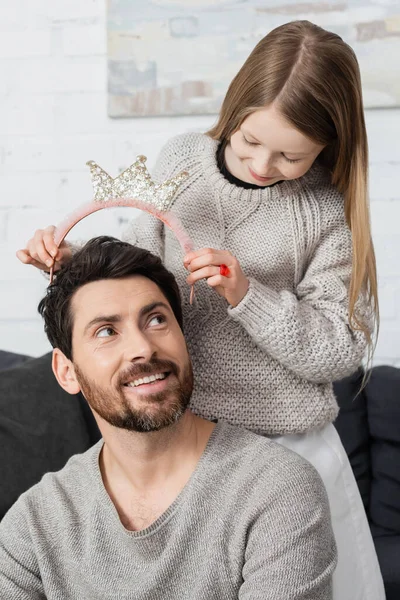 Happy preteen girl wearing crown on head of joyful father with beard — Photo de stock