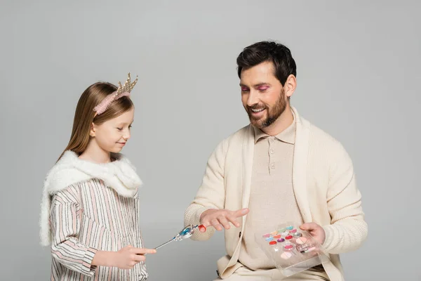 Cheerful kid in crown holding toy wand near ring of father while playing game isolated on grey — Stock Photo