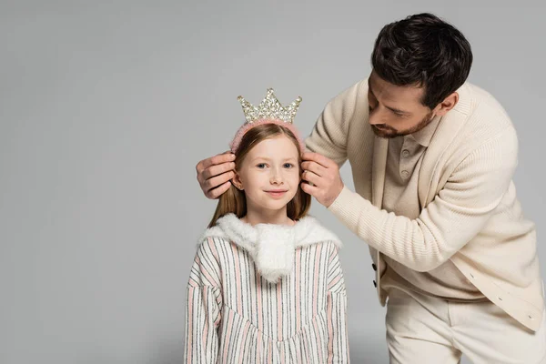 Bearded father adjusting crown of smiling daughter in dress isolated on grey — Stock Photo