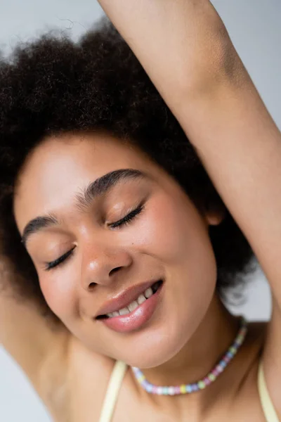 Portrait de femme afro-américaine souriante aux yeux fermés isolé sur gris — Photo de stock