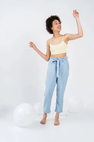 Young african american woman standing near balloons on grey background — Stock Photo