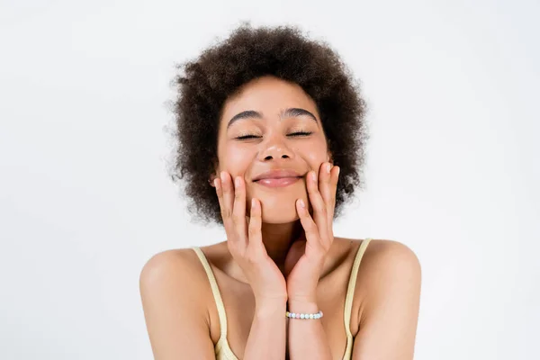 Задоволена афро-американська жінка торкається обличчя ізольованого на сірому — стокове фото
