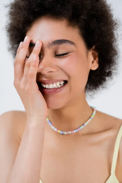 Porträt einer glücklichen afrikanisch-amerikanischen Frau, die Gesicht isoliert auf grau berührt — Stockfoto