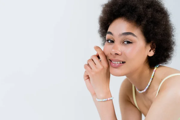 Portrait of smiling african american woman in necklace and colorful bracelet isolated on grey — Stock Photo
