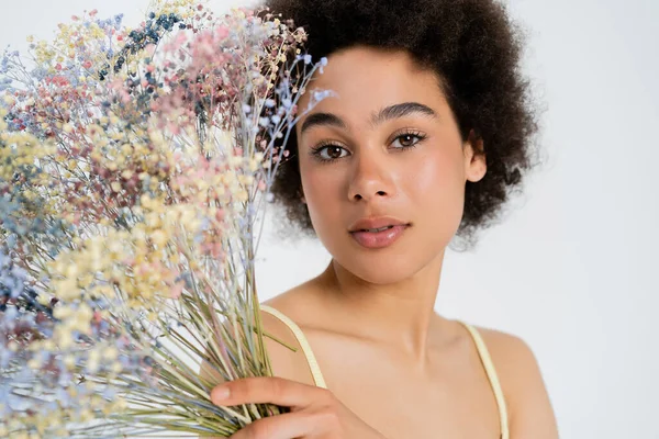 Молодая африканская американская модель позирует с цветами, выделенными на сером — стоковое фото