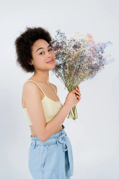 Молода афроамериканська жінка зверху, тримаючи квітки з диханням і покладаючи ізольовані на сірий — стокове фото