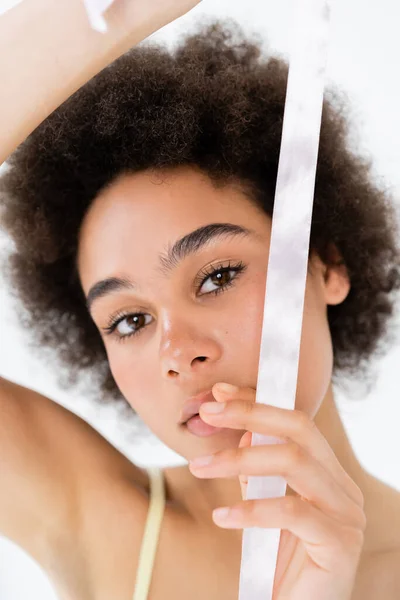 Young african american woman holding white ribbon isolated on grey — Stock Photo