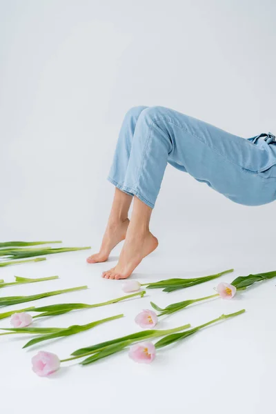 Cropped view of barefoot african american woman posing near tulips on grey background — Stock Photo