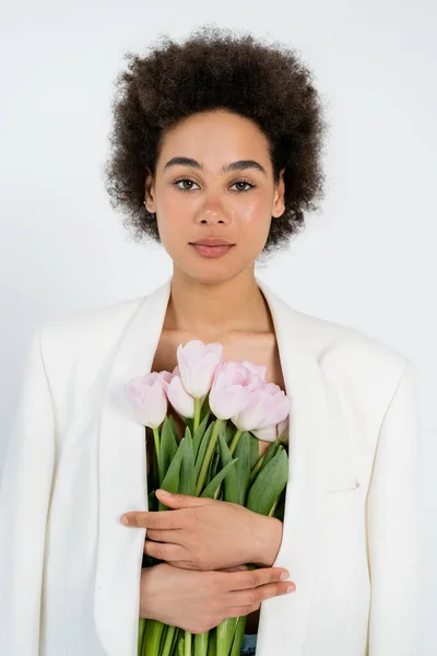 Junge Afroamerikanerin in Jacke hält Blumenstrauß isoliert auf grau — Stockfoto
