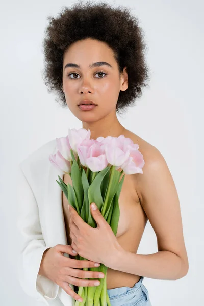 Donna afroamericana con giacca e fiori che guarda la macchina fotografica isolata sul grigio — Foto stock
