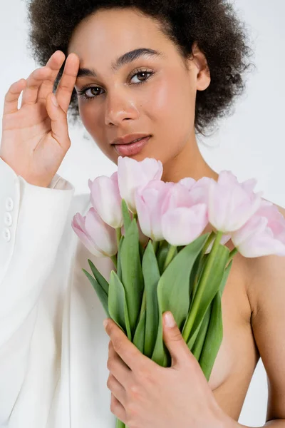 Portrait of african american model in jacket holding bouquet isolated on grey — Stock Photo
