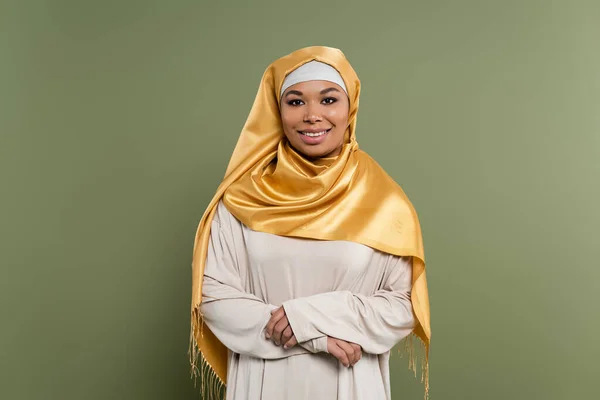Улыбающаяся многорасовая женщина в хиджабе смотрит в камеру на зеленом фоне — стоковое фото