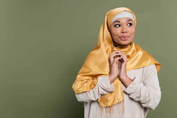Femme multiraciale rêveuse dans le hijab regardant loin sur fond vert — Photo de stock