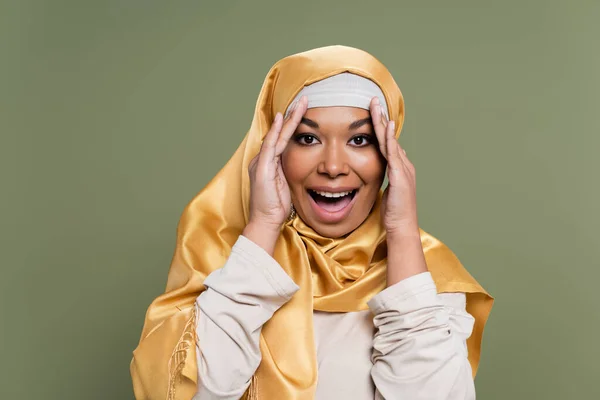 Femme multiraciale excitée en hijab jaune regardant la caméra isolée sur vert — Photo de stock