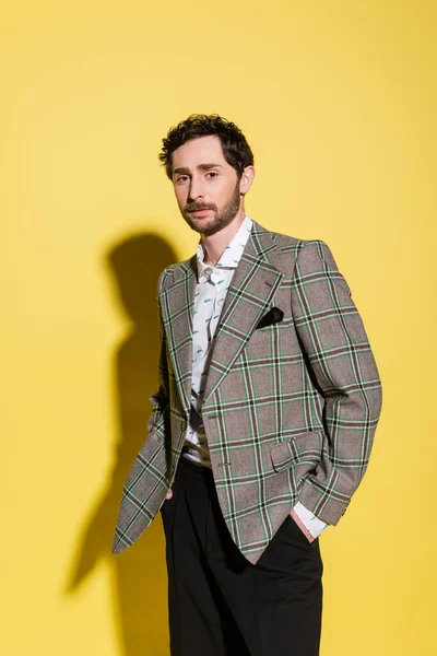 Stylish man in plaid jacket posing on yellow background with shadow — Stock Photo