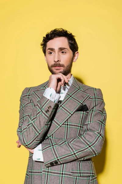 Portrait of stylish model in checkered jacket posing on yellow background — Stock Photo