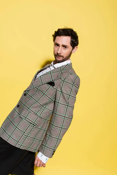 Stilvoller Mann in karierter Jacke posiert auf gelbem Hintergrund mit Schatten — Stockfoto