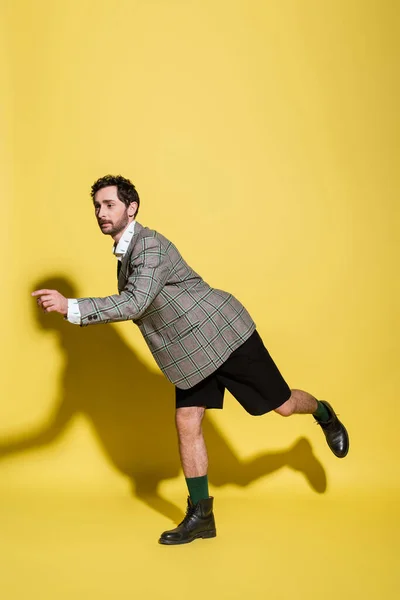 Modello alla moda in pantaloncini e giacca a quadri in posa su sfondo giallo — Foto stock