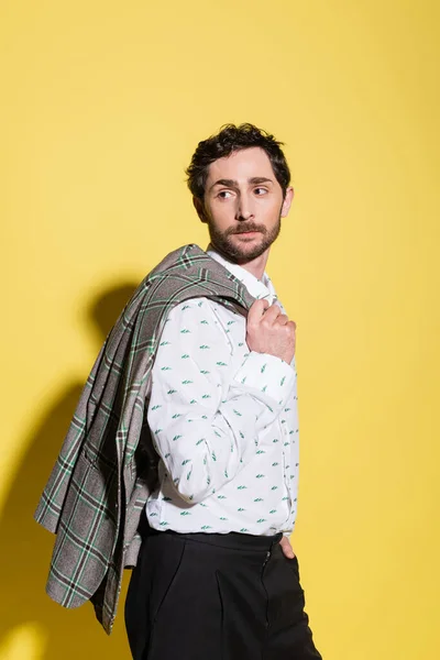 Trendy model in shirt holding checkered jacket on yellow background — Stock Photo