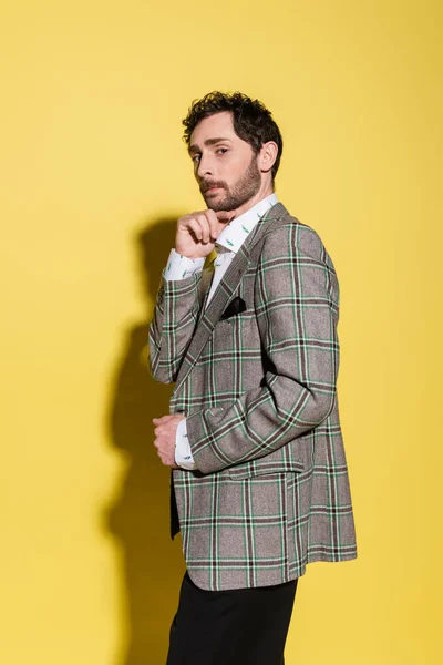 Бородата модель в стильній плетеній куртці дивиться на камеру на жовтому тлі — стокове фото