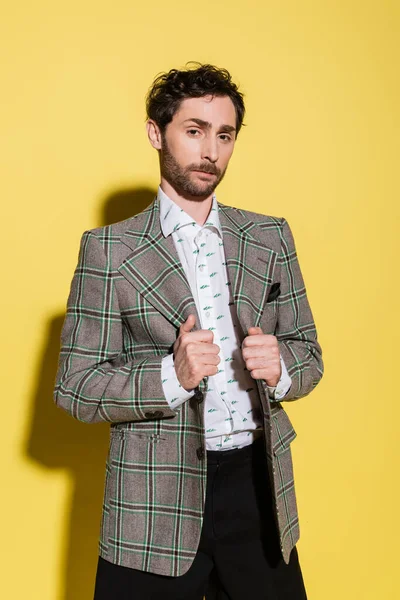 Bearded model adjusting jacket and looking at camera on yellow background — Stock Photo