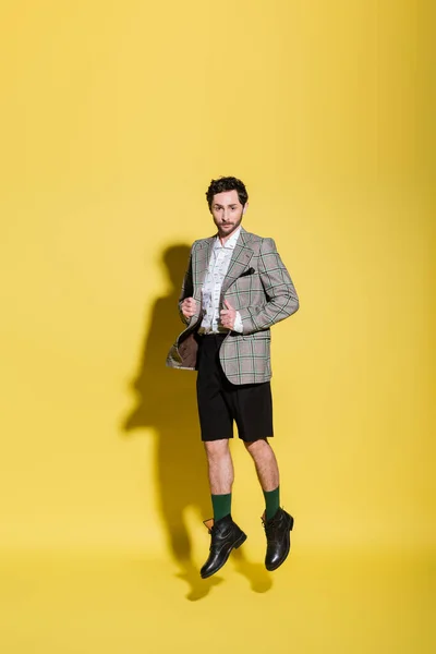 Fashionable model in stylish clothes jumping on yellow background — Stock Photo