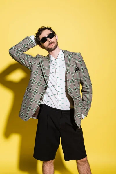 Modelo na moda posando em óculos de sol e jaqueta no fundo amarelo — Fotografia de Stock