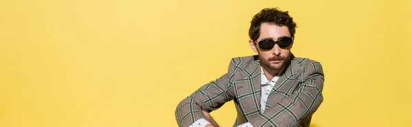 Charming guy in checkered jacket and sunglasses isolated on yellow, banner — Stock Photo