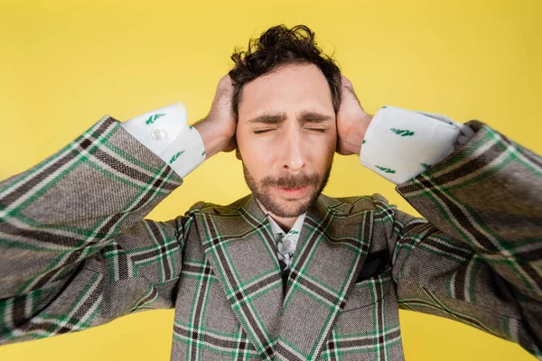 Wide angle view of stylish man covering ears isolated on yellow — Stock Photo
