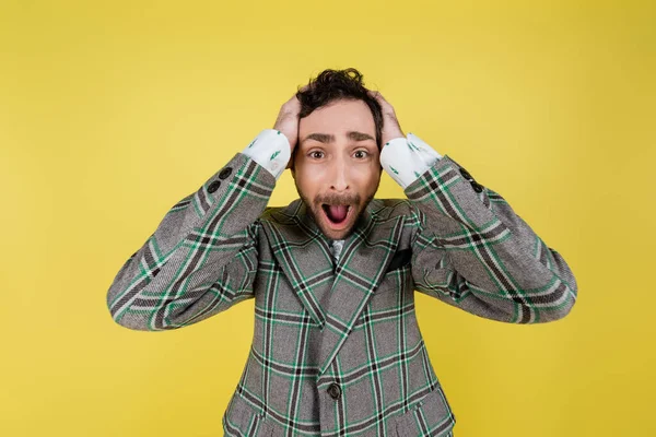 Homem gritando em casaco cobrindo orelhas isoladas em amarelo — Fotografia de Stock