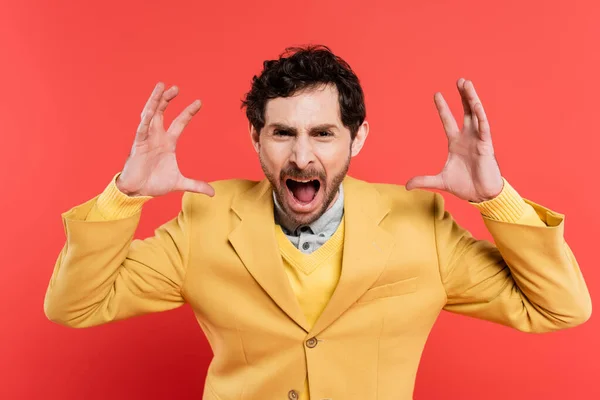 Stressed man in yellow blazer screaming and gesturing on red coral background — Stock Photo