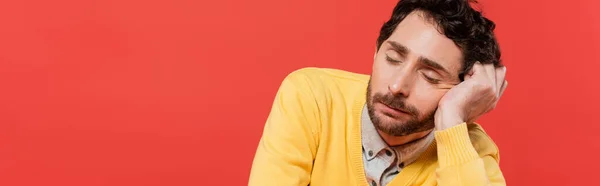 Uomo stanco in giallo maglione a maniche lunghe dormire isolato su sfondo corallo, striscione — Foto stock