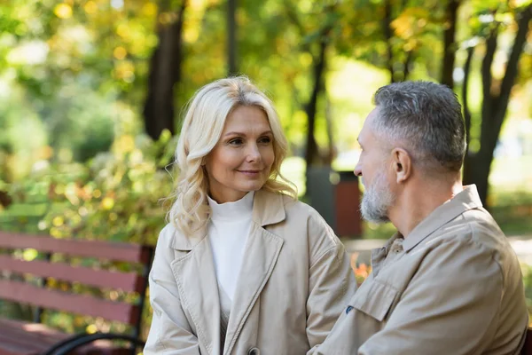 Улыбающаяся женщина средних лет смотрит на мужа в парке — стоковое фото