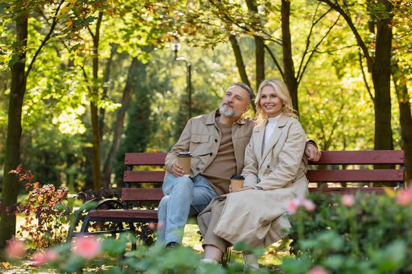 Überglückliches älteres Paar mit Kaffee zu gehen, während es Zeit im Park verbringt — Stockfoto