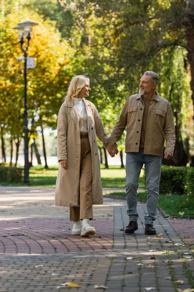 Positivo casal maduro andando e conversando no parque de outono — Fotografia de Stock