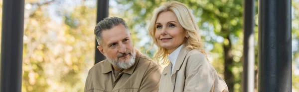 Middle aged man looking at overjoyed blonde wife in park, banner — Stock Photo