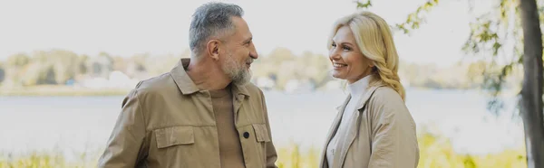 Positiv reifes Paar spricht, während sie Zeit im Park verbringen, Banner — Stockfoto