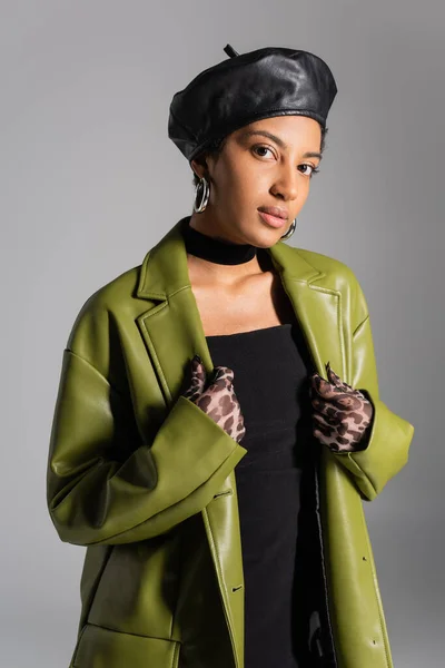 Стильна афроамериканська модель в береті та шкіряній куртці, що стоїть ізольовано на сірому — стокове фото