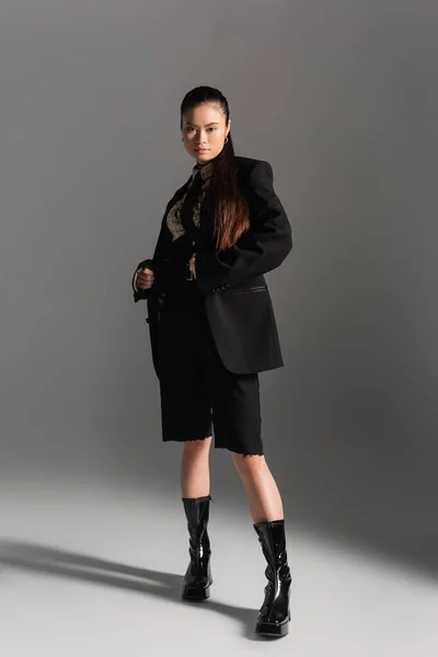 Стиль молодої азійської моделі в куртці позує на сірому фоні — стокове фото