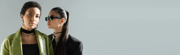 Portrait de modèle afro-américain élégant debout près d'un ami asiatique isolé sur gris, bannière — Photo de stock