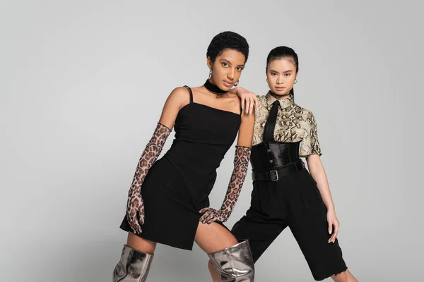 Asiatische und afrikanisch-amerikanische Freundinnen in stilvoller Kleidung posieren isoliert auf grau — Stockfoto