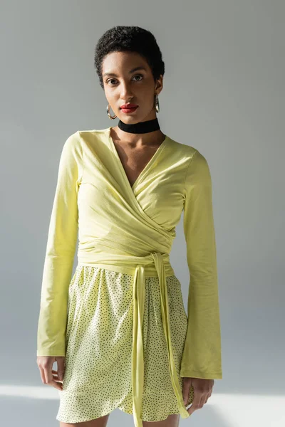 Яскраво-африканська модель на весняному одязі, що стоїть на сірому фоні. — стокове фото