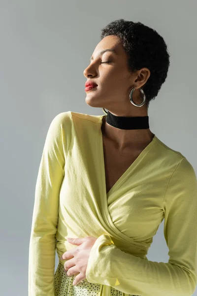 Retrato del joven modelo afroamericano posando en luz solar aislado sobre gris - foto de stock