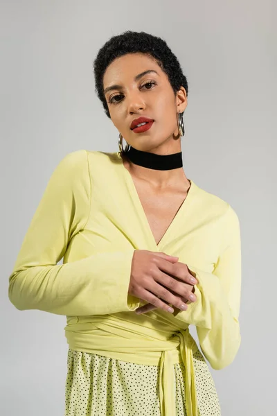 Портрет афроамериканської моделі в жовтій блузці, що стоїть ізольовано на сірому — стокове фото