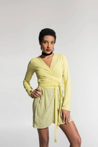 Young african american woman in yellow clothes posing isolated on grey — Stock Photo
