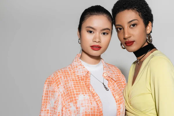 Portrait of young interracial models with red lips looking at camera on grey background — Stock Photo