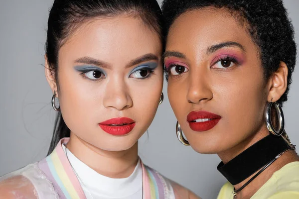 Retrato de modelos inter-raciais com maquiagem colorida em fundo cinza — Fotografia de Stock